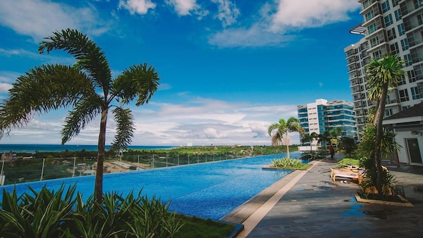 Una piscina con vista al océano y un rascacielos al fondo.