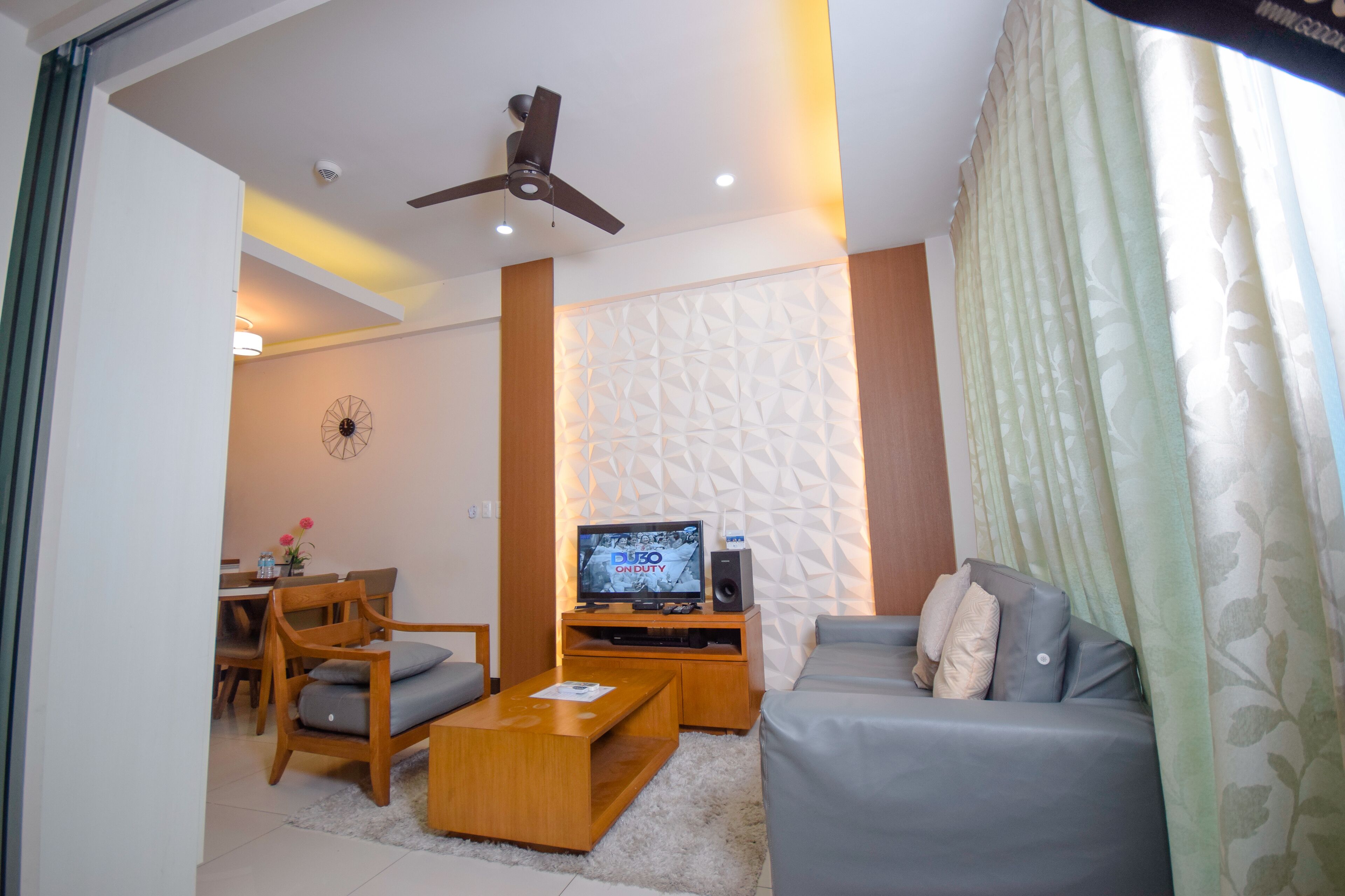 A living room with a sofa, coffee table, TV, and a ceiling fan.