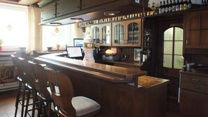 Eine Bar mit hölzernen Barhocker, einem Computer und einer Kaffeemaschine.