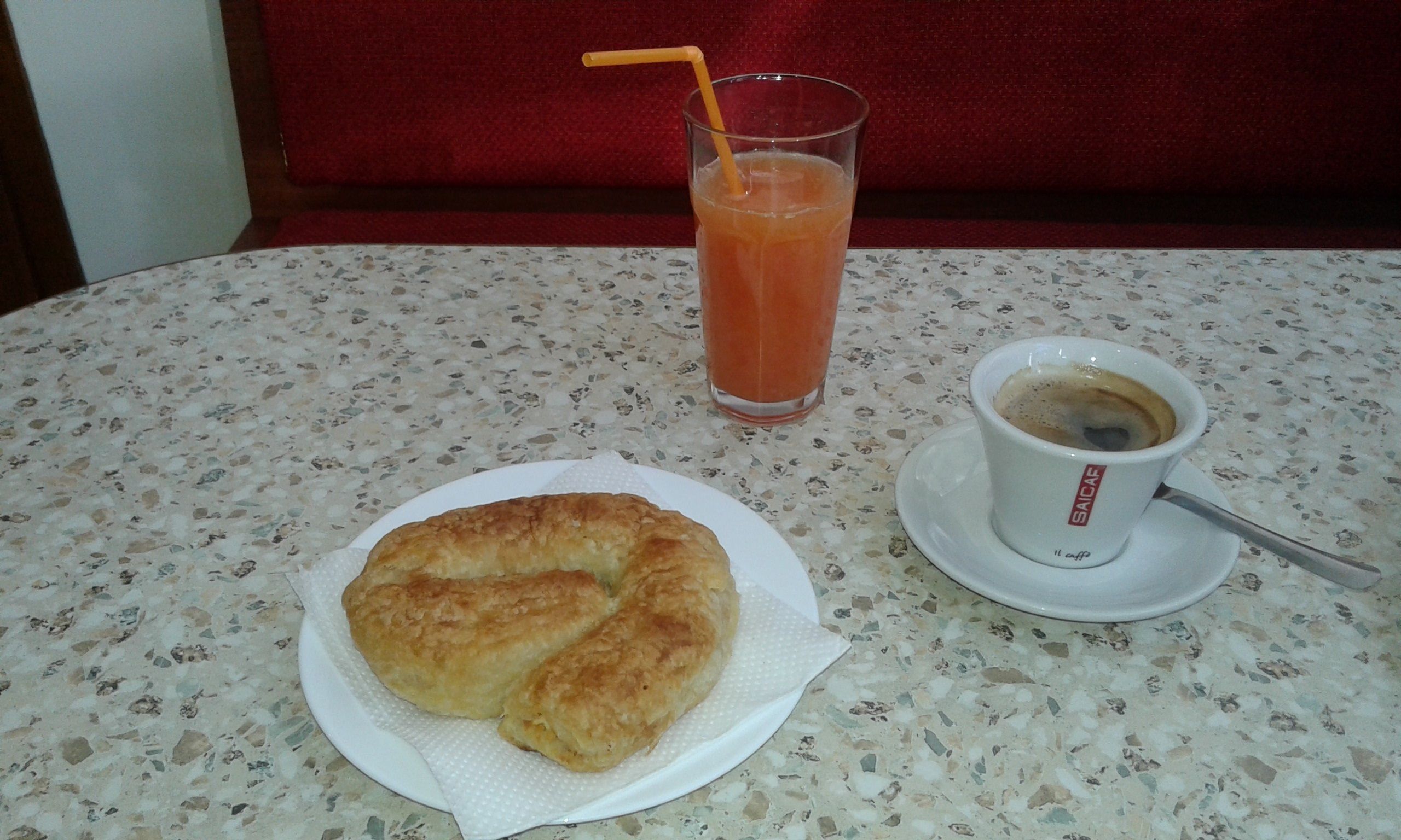 A table with a croissant, a glass of iced tea, and a cup of coffee.