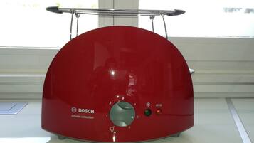 Um eletrodoméstico Bosch vermelho com painel de controle e uma alça de metal na parte superior.