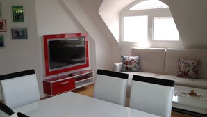 A modern living room with a television, sofa, and dining table. - Sagittarius Apartment (Kyustendil)