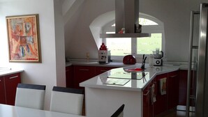 A modern kitchen with red cabinets, a white countertop, and a large window. - Sagittarius Apartment (Kyustendil)