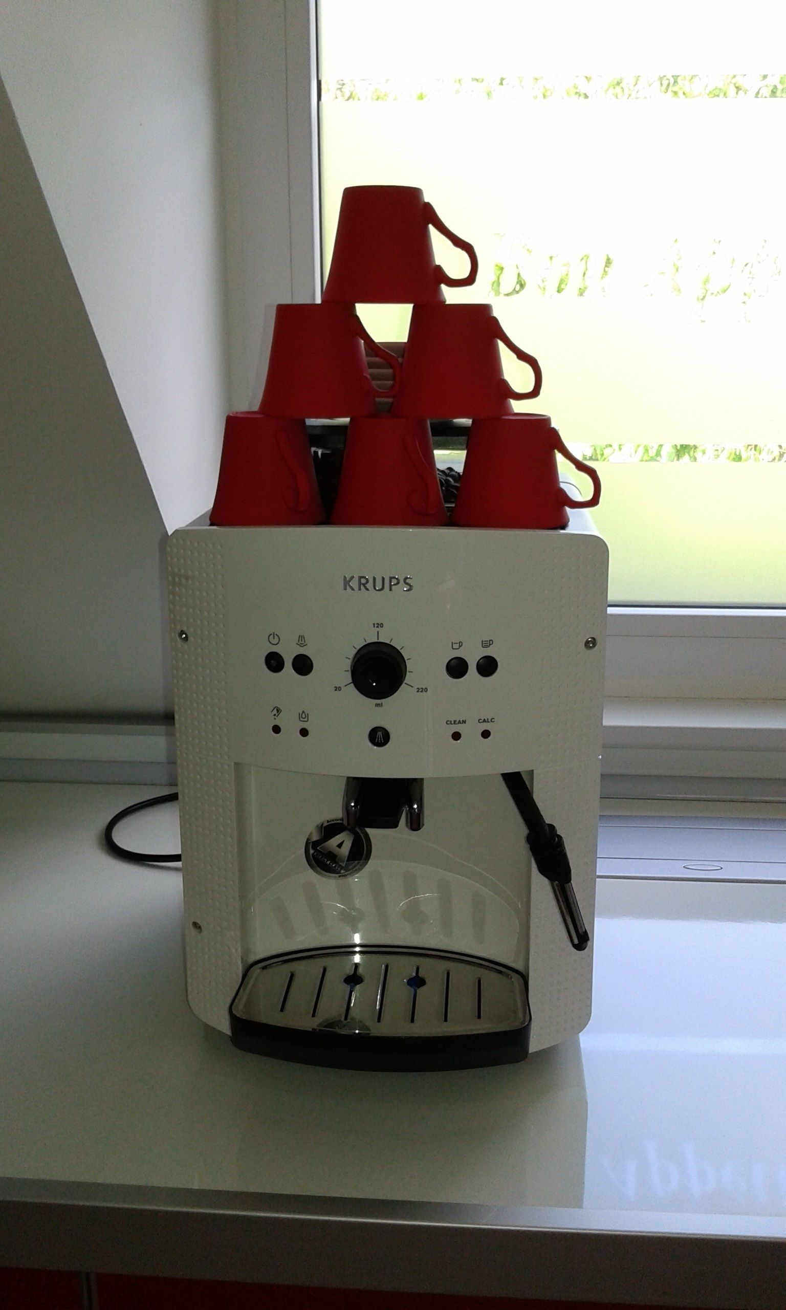 A coffee machine with a control panel and a water dispenser on a windowsill.