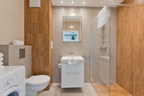 Ein modernes Badezimmer mit Waschbecken, Toilette und Waschmaschine in Weiß.