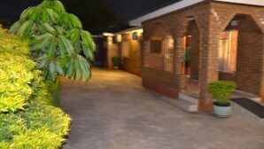 A brick building with a covered walkway and potted plants. - Jasper Guest House (Selebi-Phikwe)