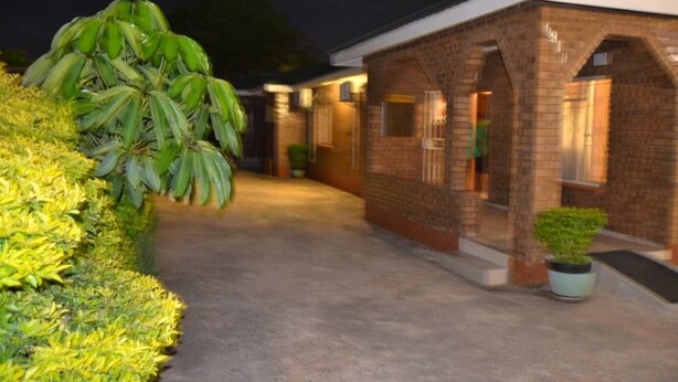 Un edificio de ladrillo con un corredor cubierto y plantas en macetas.