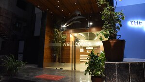 A modern hotel entrance with a wooden ceiling, potted plants, and a reception desk. - The Pacific Hotel, Vadodara (Vadodara)