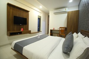 Habitación de hotel con cama, escritorio, silla, televisor montado en la pared y aire acondicionado.