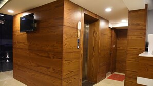 A wooden-paneled elevator with a digital display and a telephone. - The Pacific Hotel, Vadodara (Vadodara)