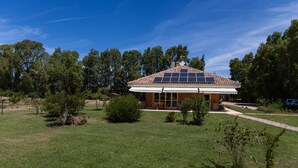 A house with a tiled roof, solar panels, and a covered porch. - Villa Arzilla Sardegna (Alghero)