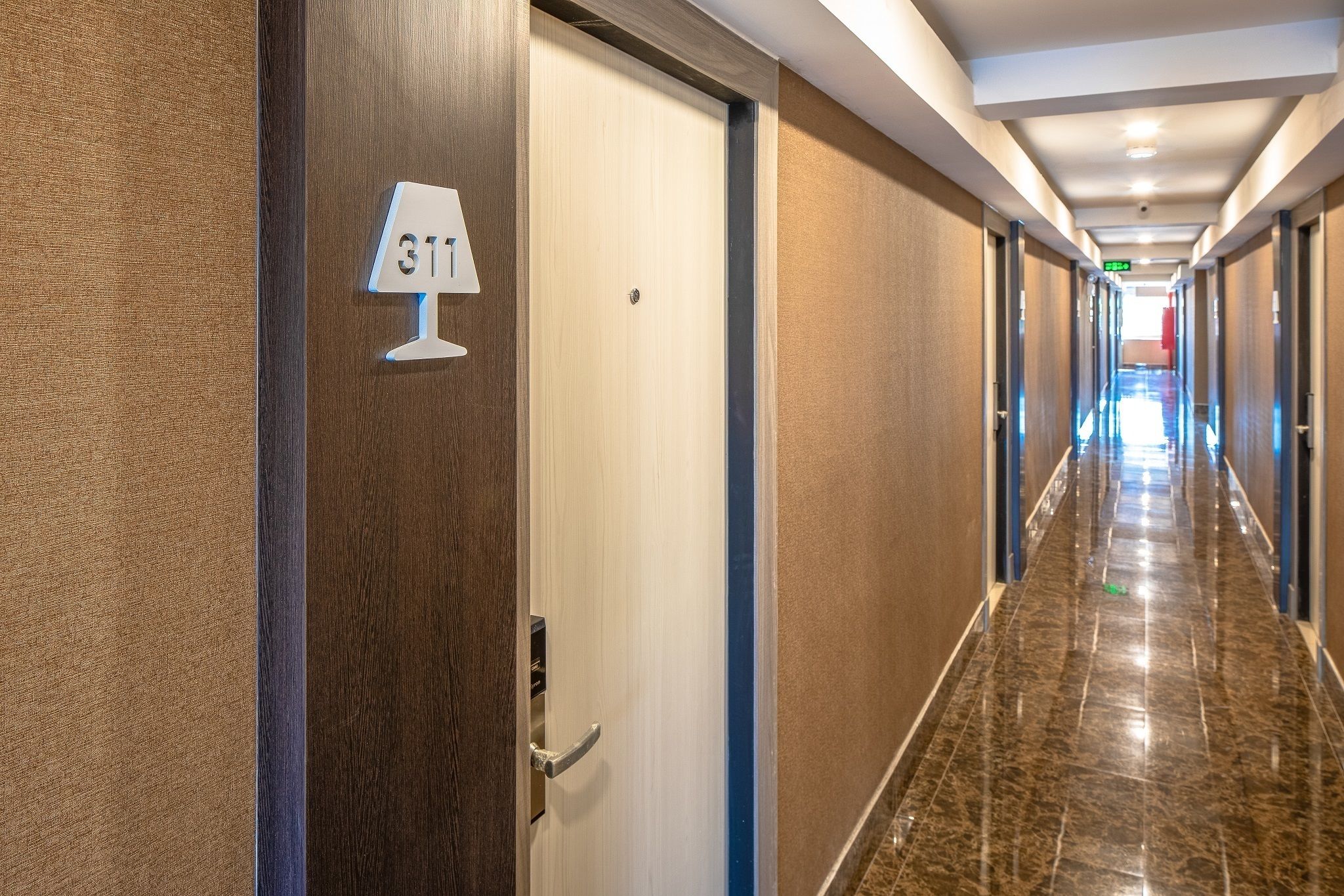 A hotel hallway with a door labeled "311" and a lamp above it.