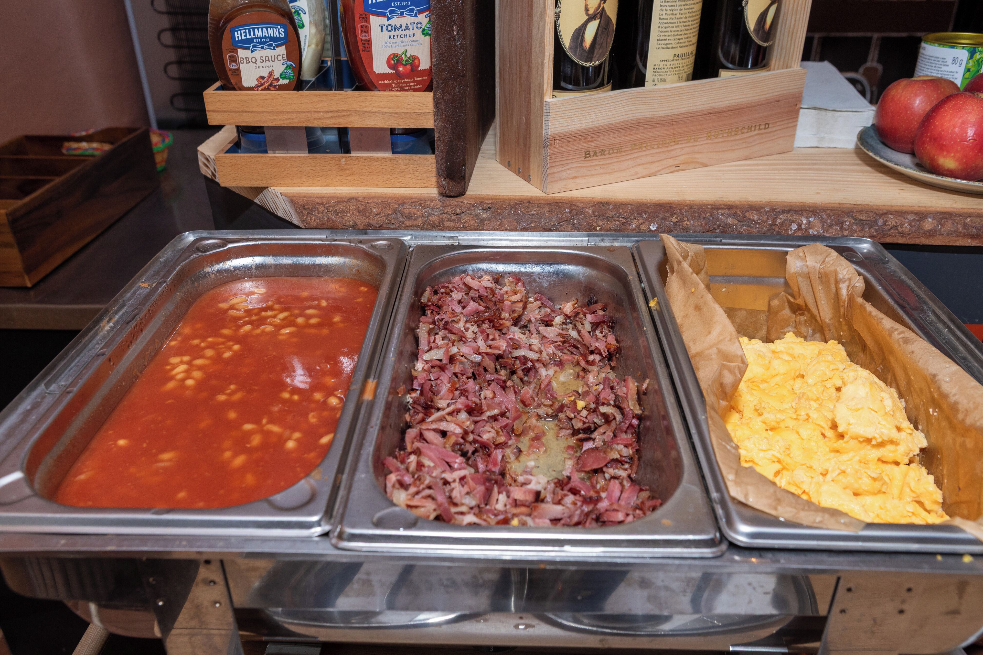 A buffet with three food dispensers: one with red sauce, one with diced meat, and one with scrambled eggs.