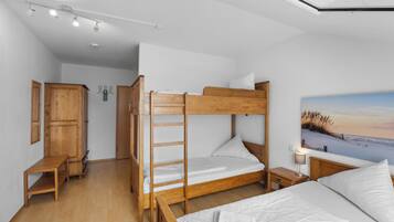 Ein Schlafzimmer mit Etagenbetten, einer hölzernen Bank, einem Nachttisch und einem Bild von einer Strandlandschaft.