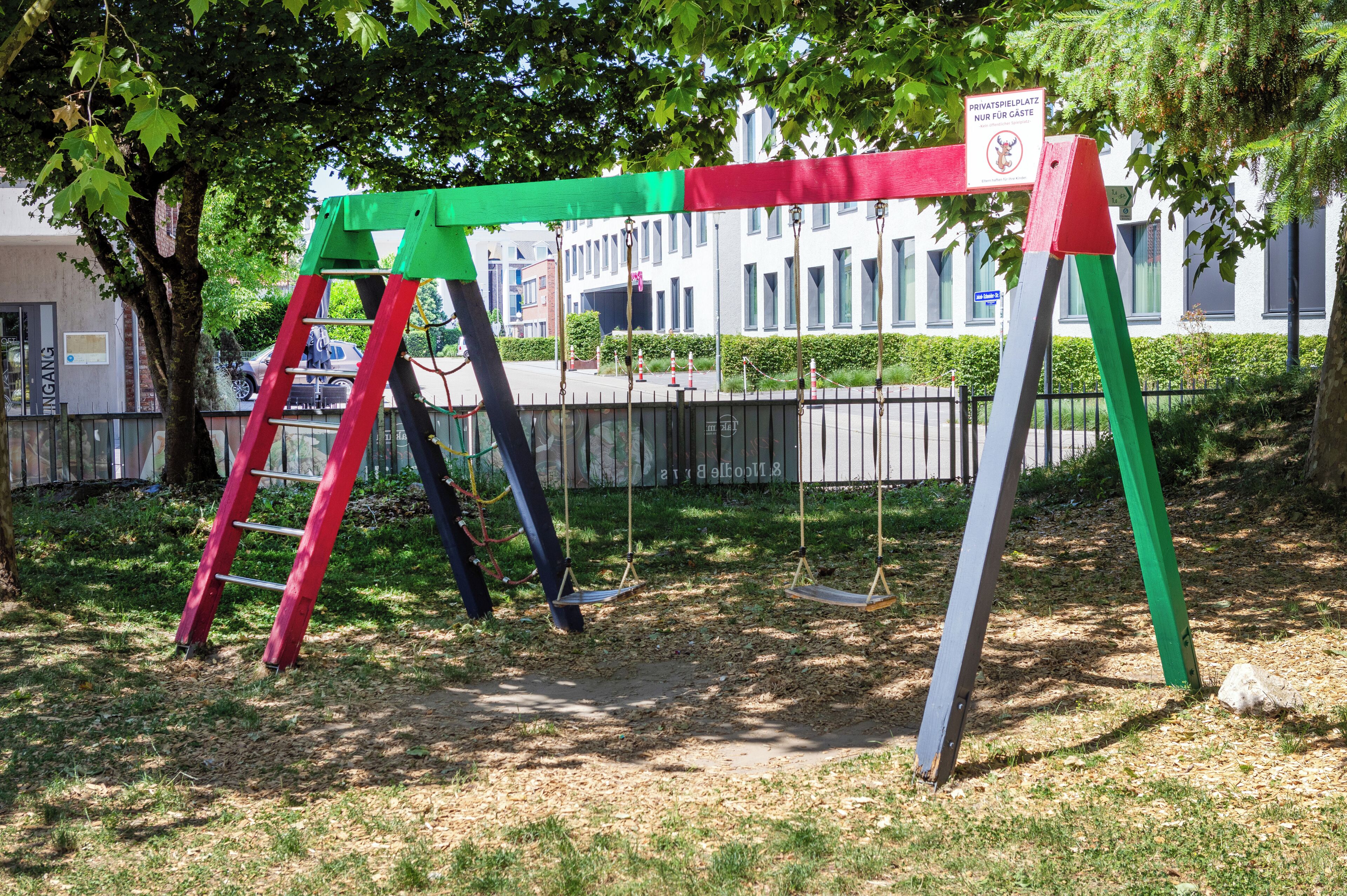 A playground with swings and a red ladder.