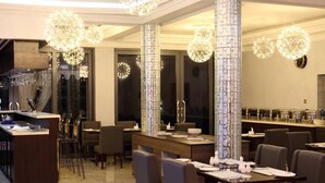Ein moderner Essbereich mit hohen Decken, dekorativen Kristalllüstern und einem Buffet.