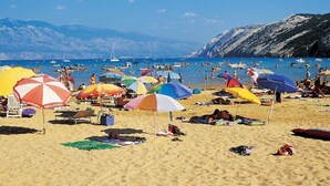 Une plage avec de nombreux parasols colorés et des gens qui se détendent.