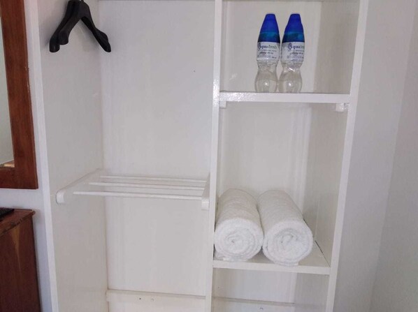 Un armario blanco con barra para colgar y estantes.