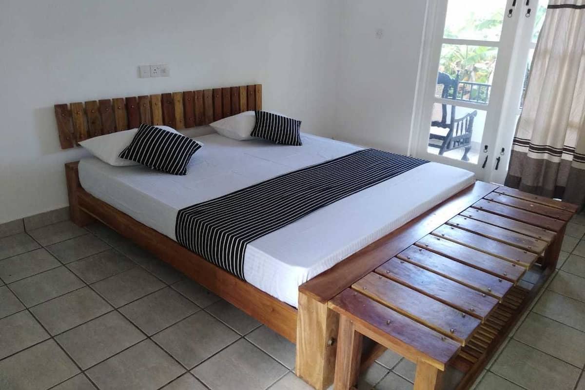 A bed with a wooden frame, two pillows, and a striped blanket.