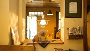 A reception area with a wooden bench, a hanging light fixture, a framed certificate, and a wall-mounted information board. - Hotel Kolonieschänke (Burg (Spreewald))