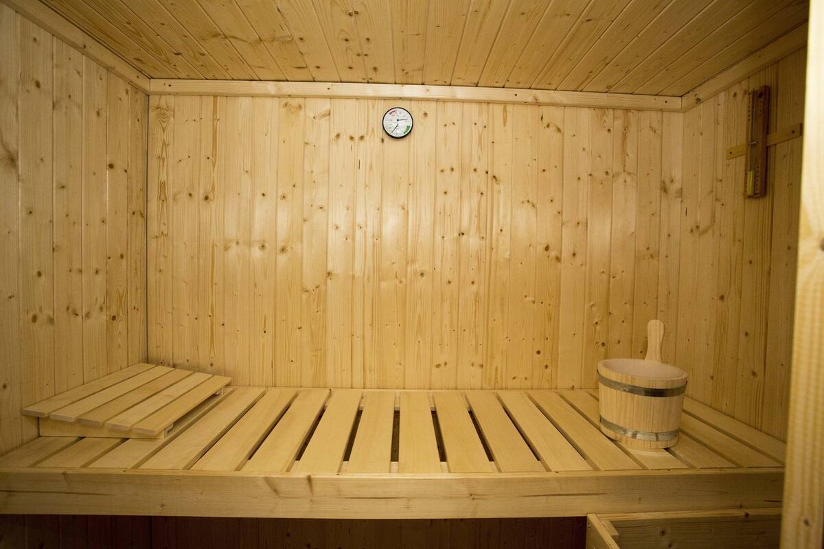 Un sauna en bois avec un banc et un seau.