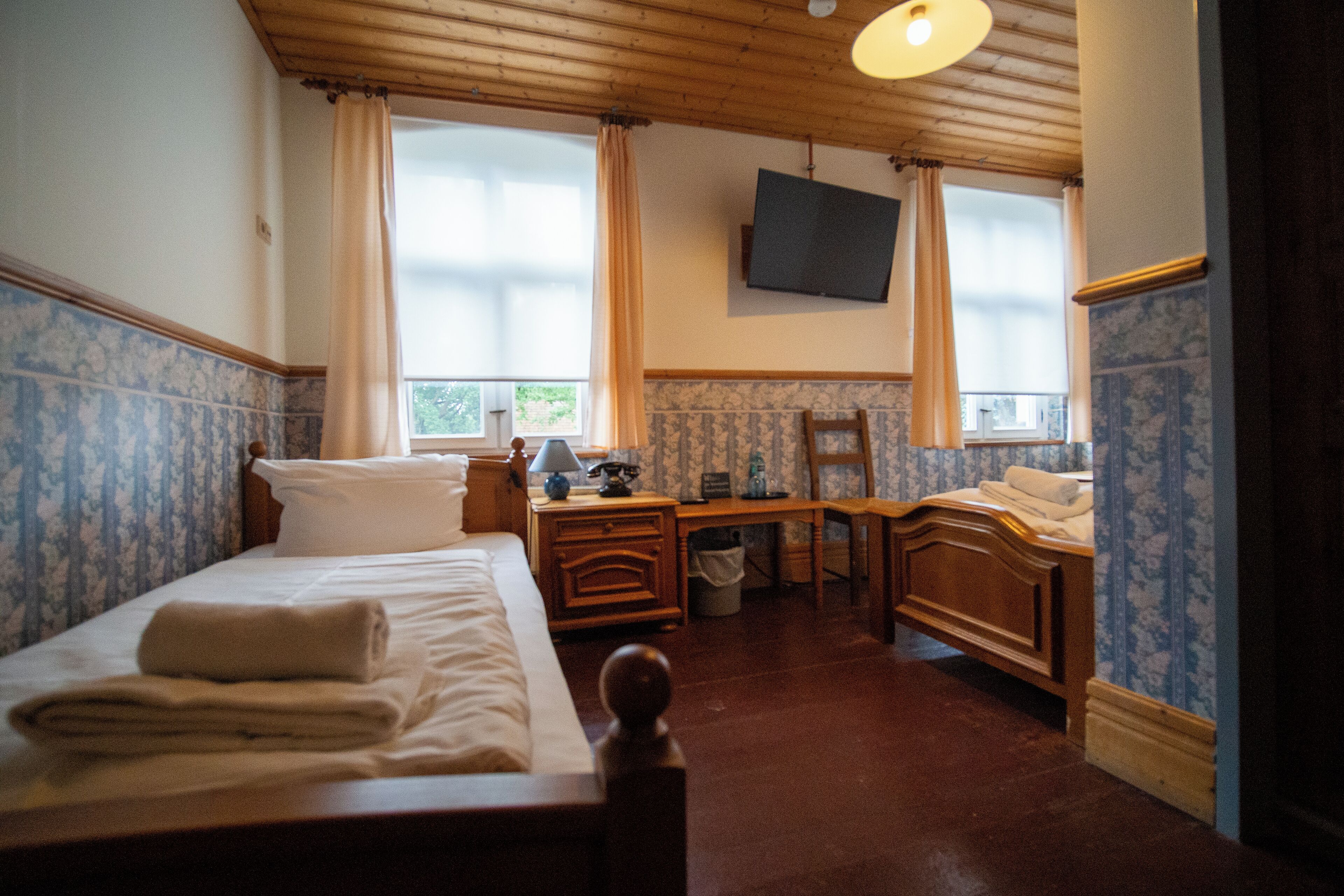A hotel room with a bed, a desk, a chair, a television, and a window with curtains.
