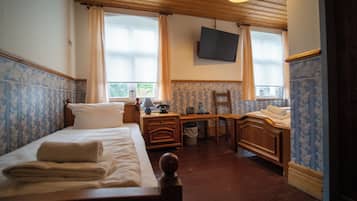 A hotel room with a bed, a desk, a chair, a television, and a window with curtains.
