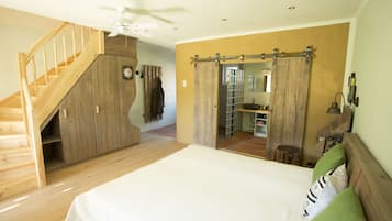 Ein Schlafzimmer mit einer Holztreppe, einem großen Bett und einem durch eine Schiebetür erreichbaren Badezimmer.