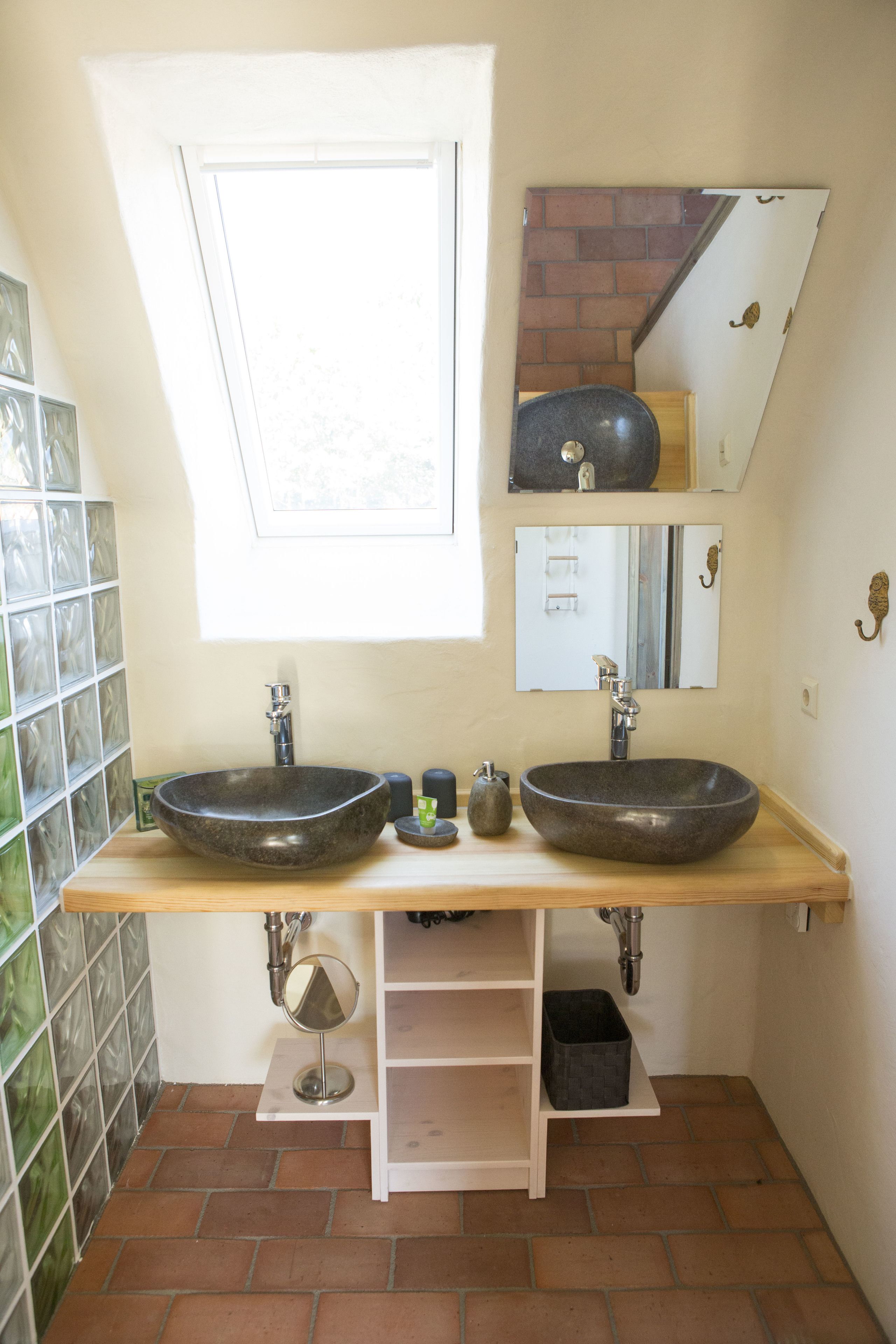 Un baño con dos lavamanos sobre encimera, una ventana y un espejo.