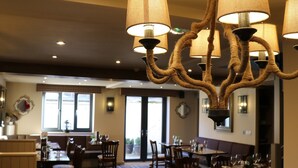 Un restaurante con candelabro, mesas de comedor, sillas y piso a cuadros.