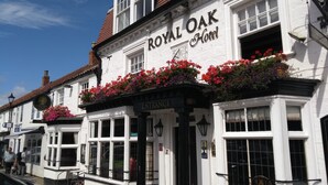Exterior del Hotel Royal Oak, con fachada tradicional, macetas con flores y un cartel que indica la entrada.