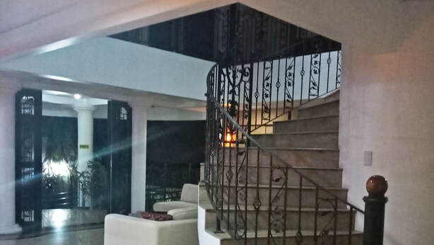 Un amplio vestíbulo con una escalera curva y un sofá blanco.