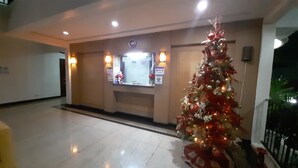 Un vestíbulo con un árbol de Navidad, una recepción y un reloj en la pared.