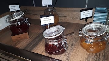 A wooden table with jars of marmalade and jam, each labeled with the type of fruit used.