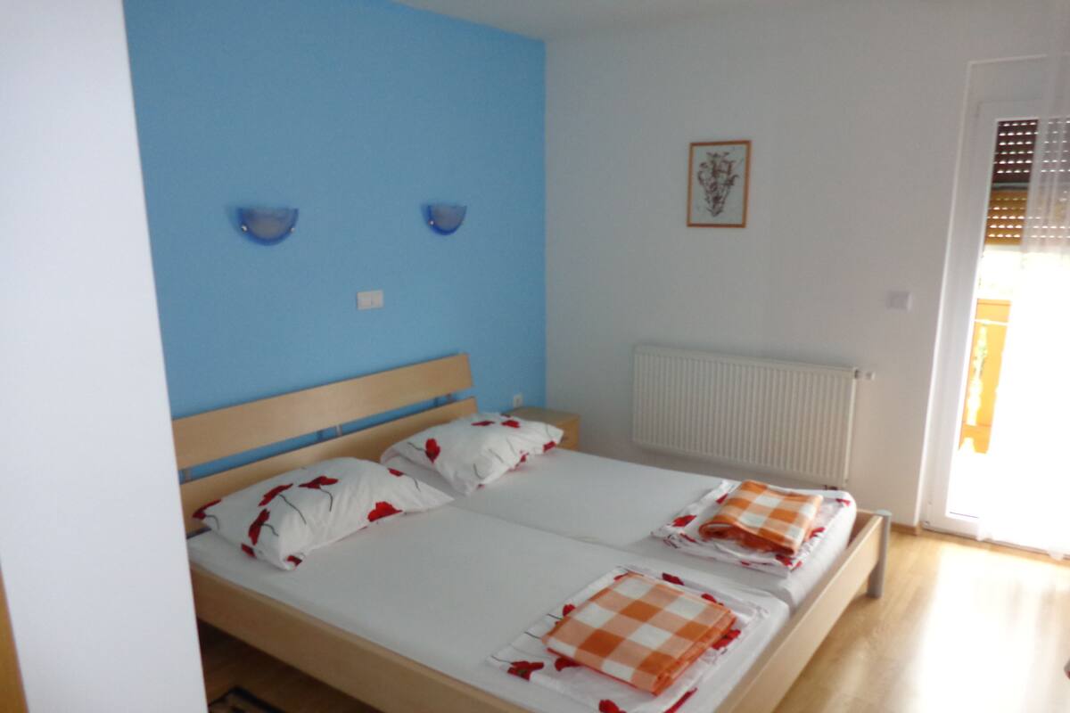 Un dormitorio con cama de madera, ropa de cama blanca y pared azul.