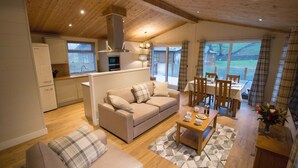 A cozy living area with a sofa, a dining table, and a kitchen in the background. - Hendre Rhys Gethin (Betws-Y-Coed)