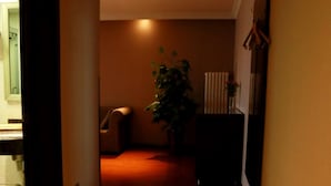 A hallway with a radiator, a chair, and a potted plant. - GreenTree Inn Jinan Gaoxin District International Convention Centre Hotel (Jinan)