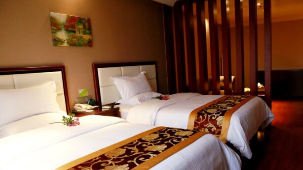 A hotel room with two beds, a wooden floor, and a painting on the wall. - GreenTree Inn Jinan Gaoxin District International Convention Centre Hotel (Jinan)