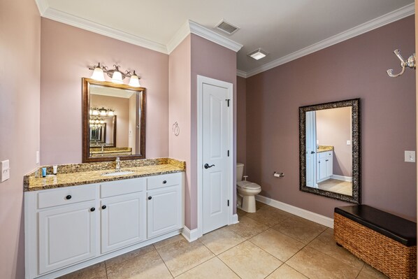 A bathroom with a vanity, sink, mirror, and toilet.