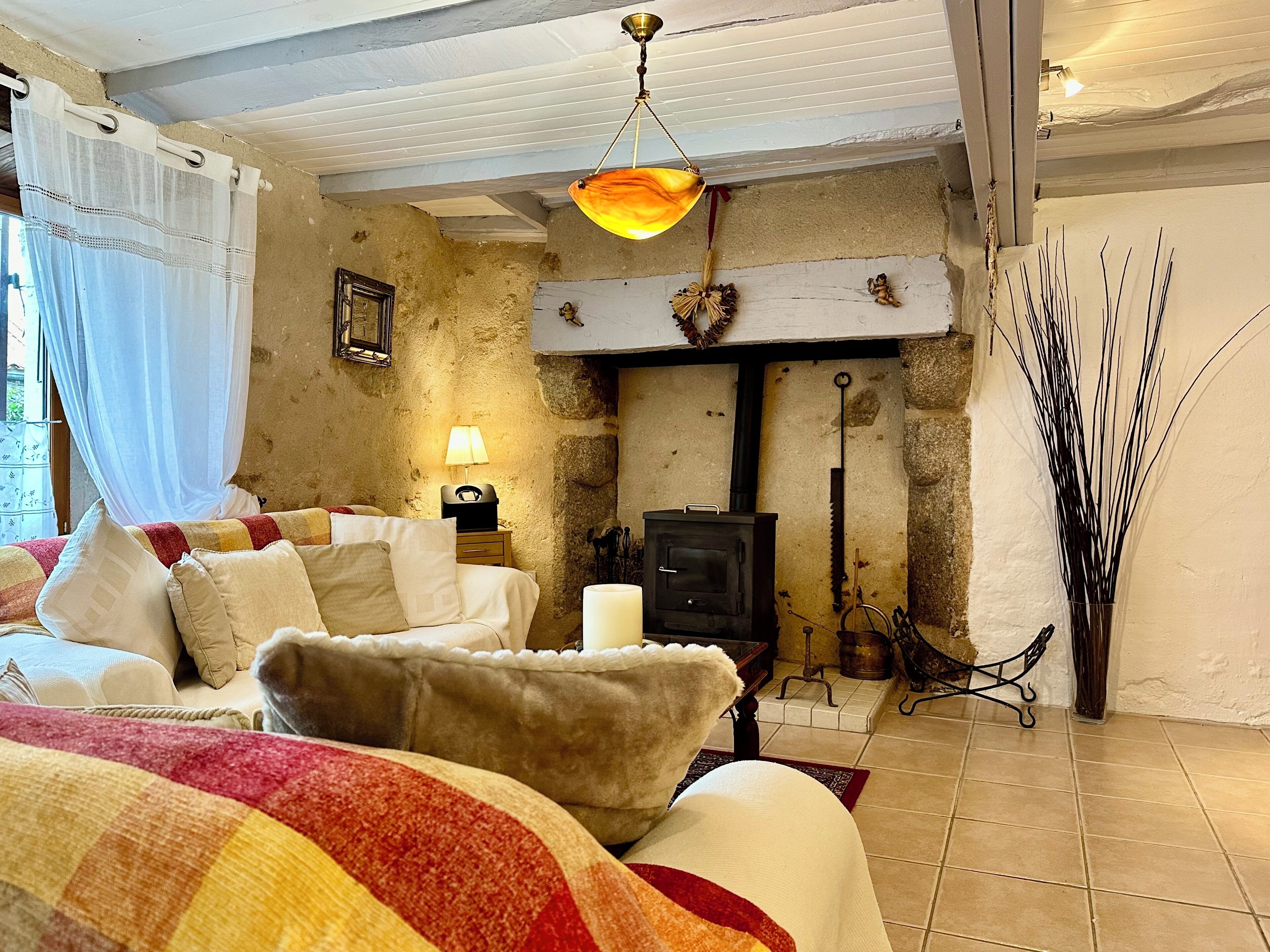 A cozy bedroom with a bed, a lamp, a fireplace, and a rustic decor.