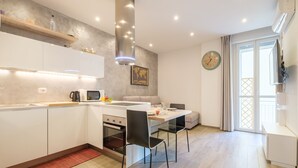 Una cocina moderna con armarios blancos, horno empotrado y zona de comedor con dos sillas negras.