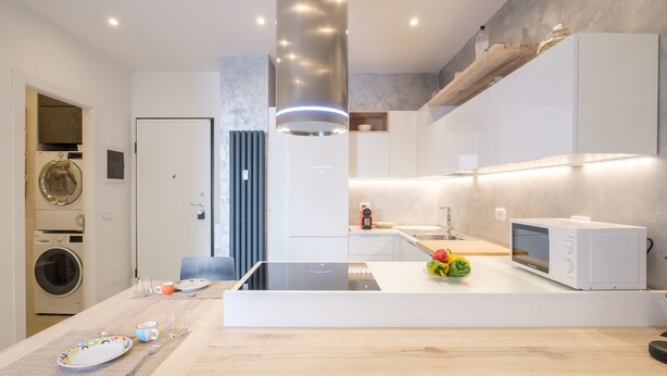 Una cocina moderna con una isla central, electrodomésticos integrados y un comedor.