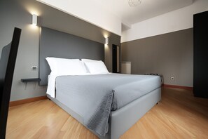 A modern bedroom with a bed, bedside tables, and wall-mounted lighting. - Piazza Carità (Naples)