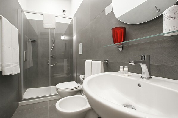 Une salle de bain moderne avec une douche à parois de verre, un lavabo blanc et des toilettes.