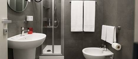 Une salle de bain moderne équipée d’une douche, de deux lavabos et de toilettes.