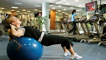 Une salle de sport équipée de matériel d’exercice, notamment un ballon d’exercice bleu et des tapis de course.