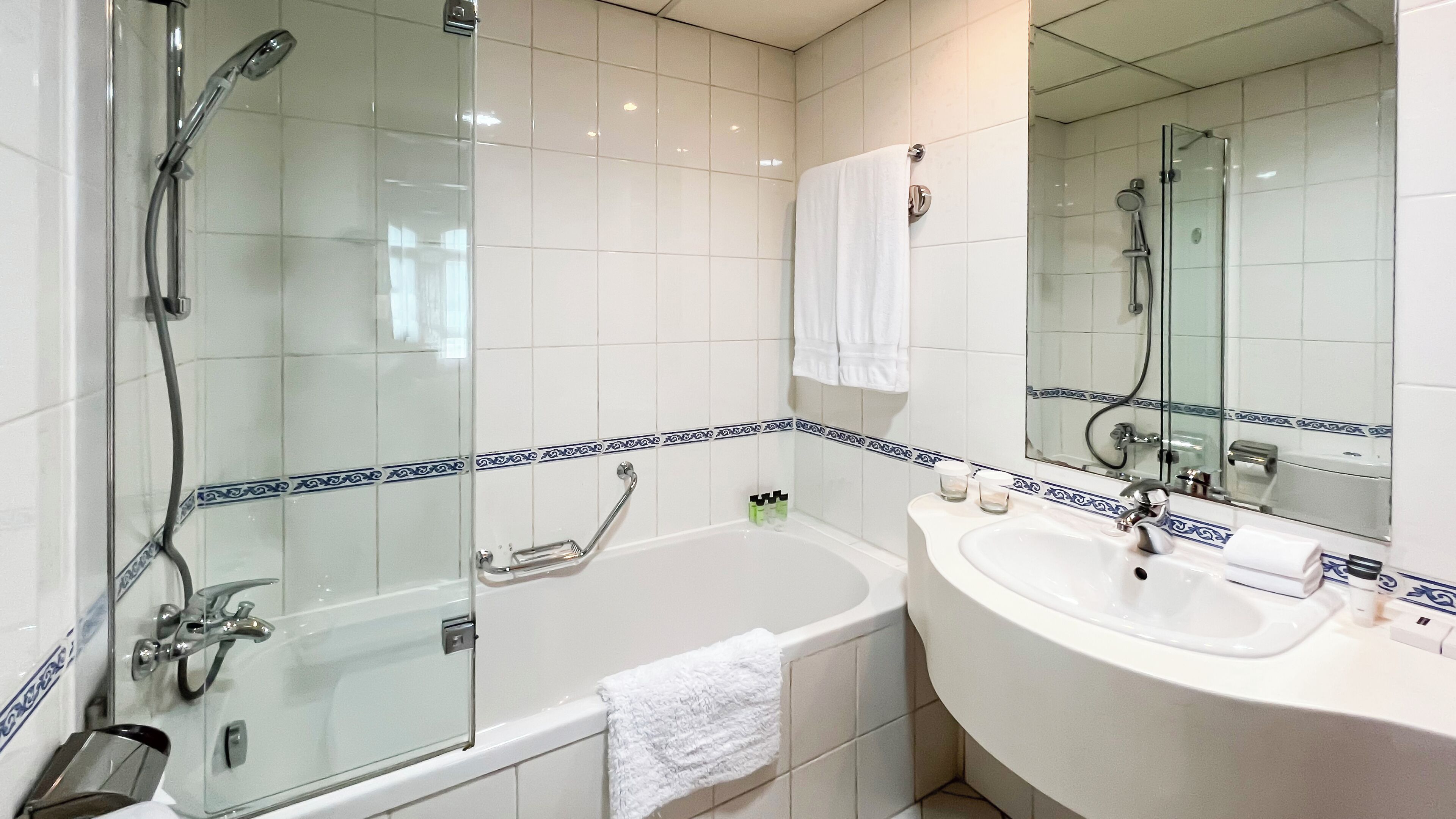 Un baño moderno con ducha de vidrio, una bañera independiente y un tocador con lavabo y espejo.