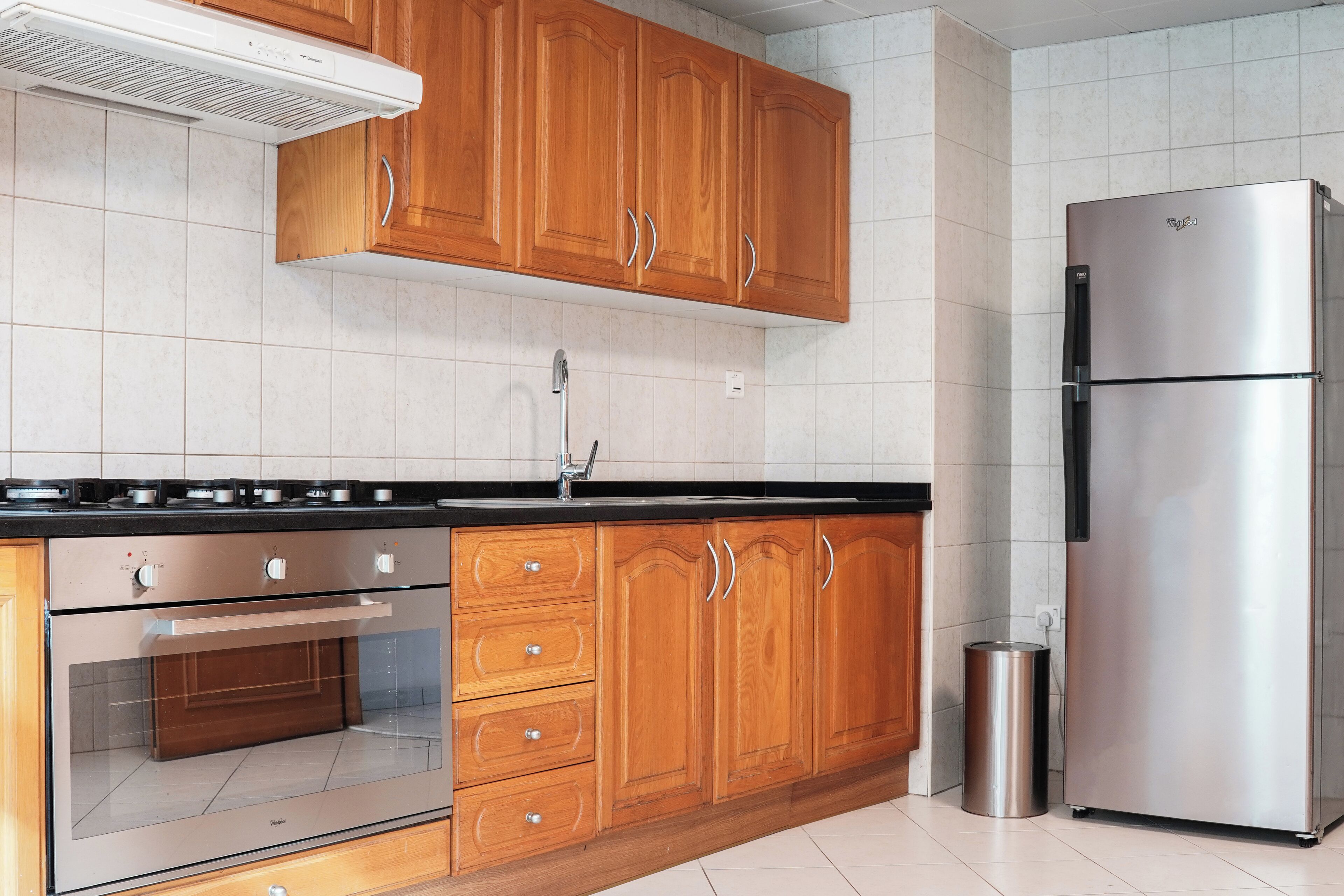 A kitchen with wooden cabinets, a stainless steel refrigerator, a built-in oven, and a gas stove.