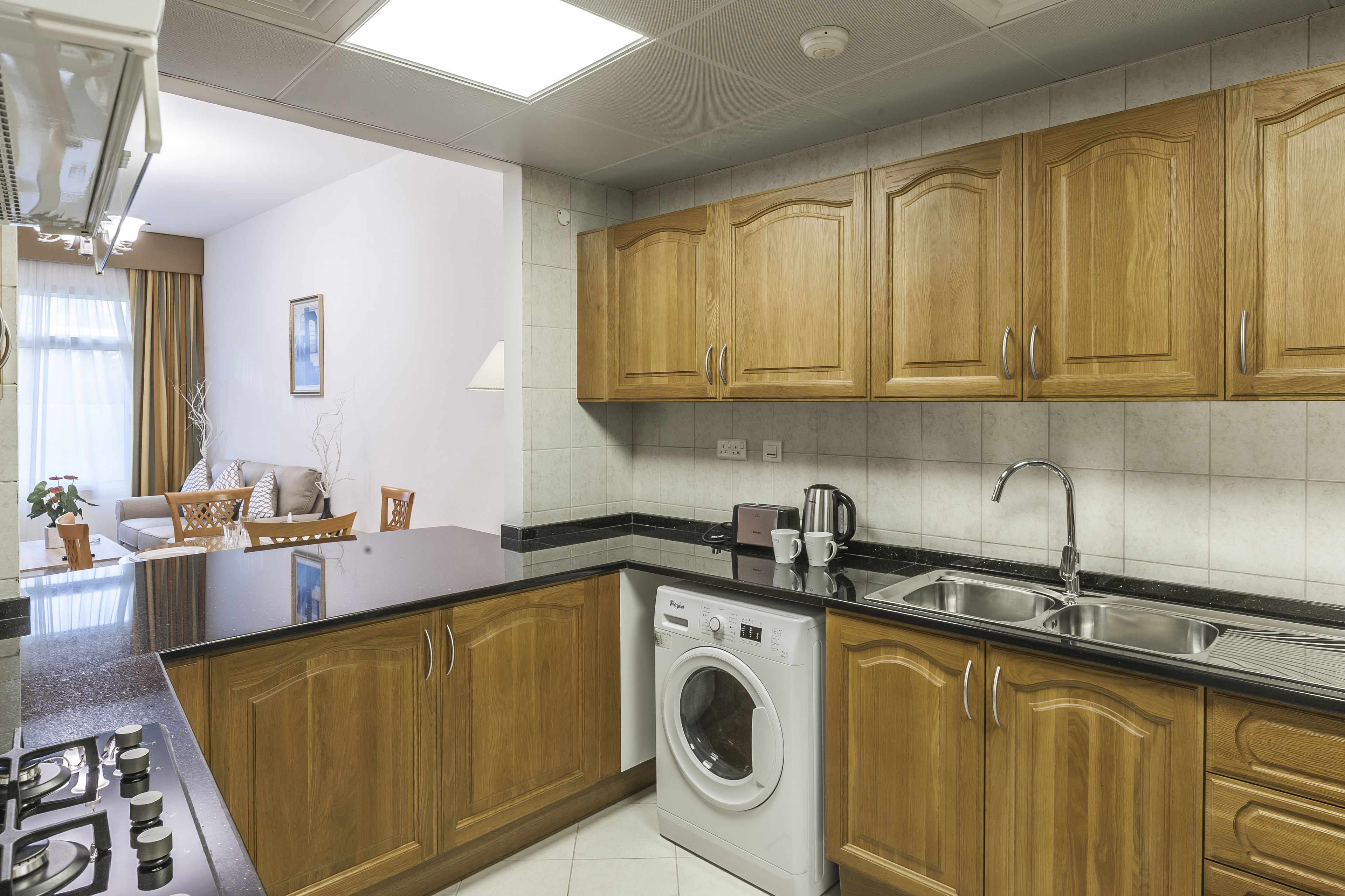 Une cuisine moderne avec des meubles en bois, un lave-linge encastré et un grand îlot central doté d’un évier.