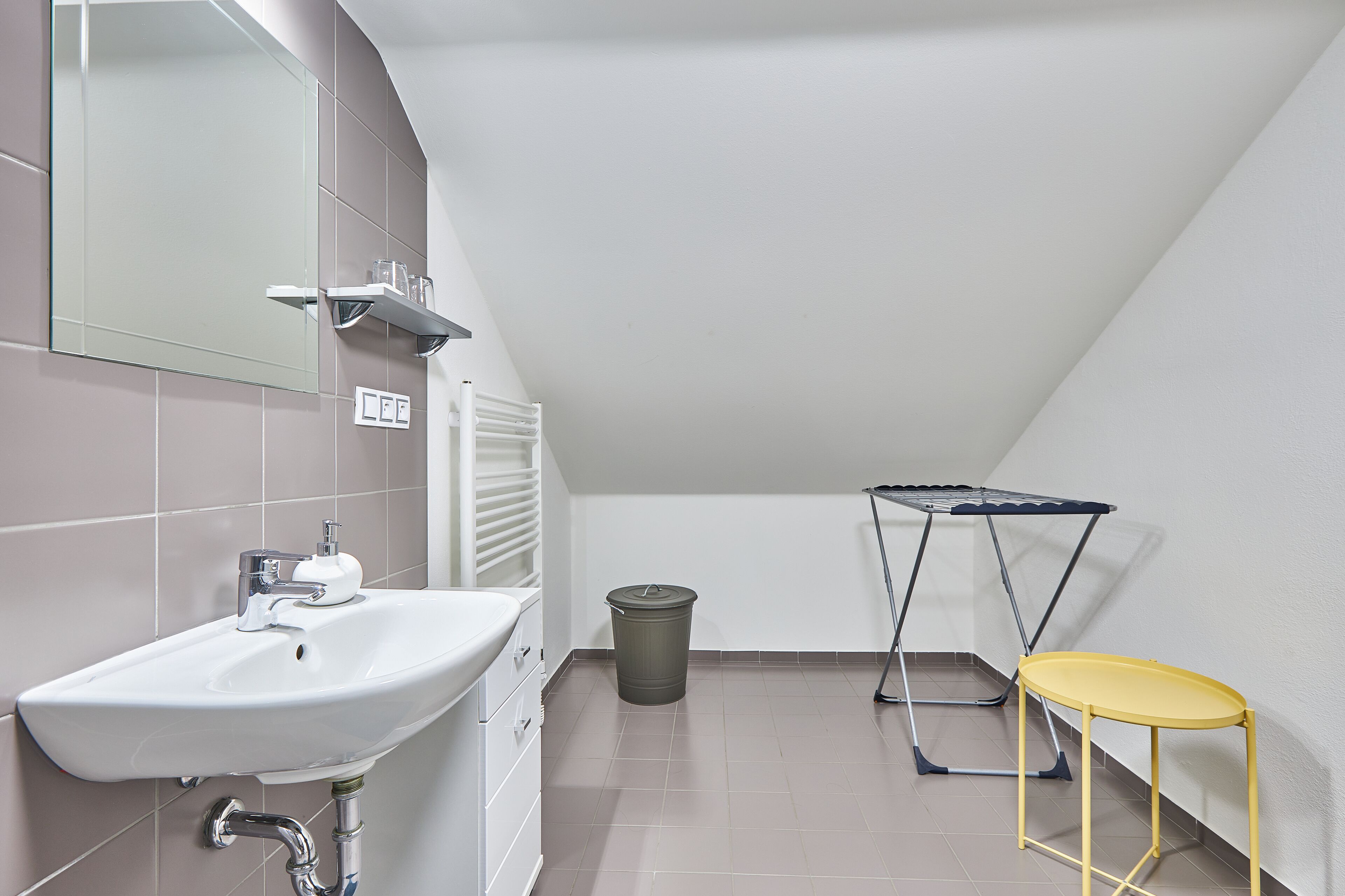 A small bathroom with a sink, mirror, and a drying rack.